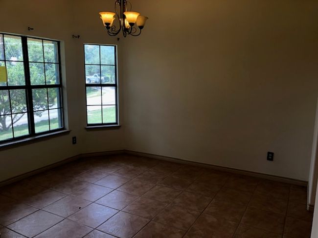 Dining room with a chandelier, dark tile patterned floors, and baseboards | Image 5