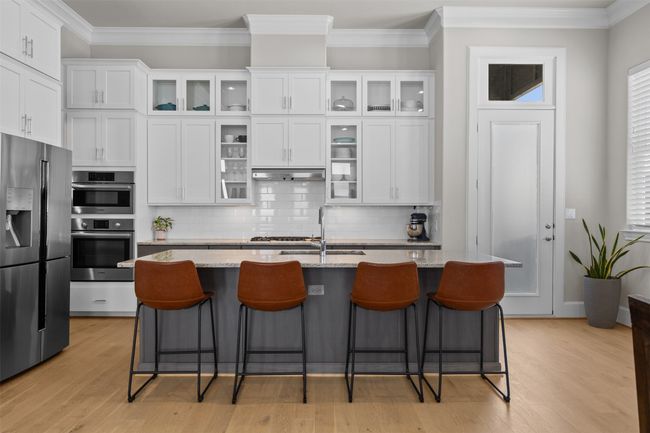 Kitchen featuring stainless steel appliances, white cabinetry, decorative backsplash, and crown molding | Image 6