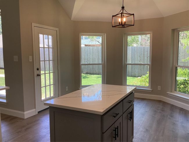 Kitchen with vaulted ceiling, wood finished floors, plenty of natural light, and a chandelier | Image 13