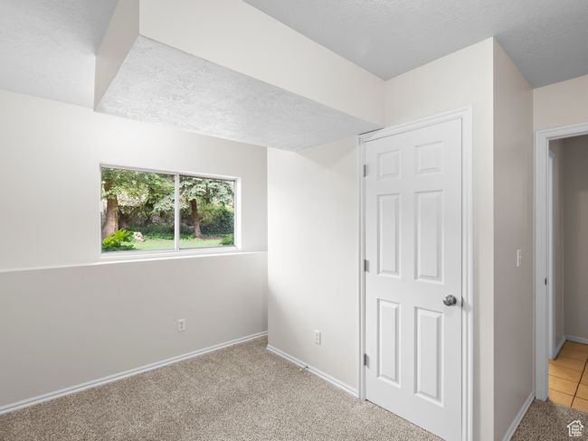 Unfurnished bedroom with a textured ceiling, baseboards, and light carpet | Image 20