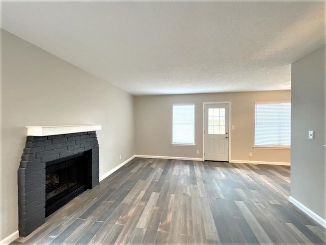 Unfurnished living room featuring a fireplace, wood finished floors, and baseboards | Image 4