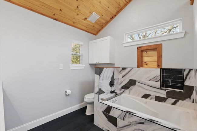 Full bathroom with wooden ceiling, toilet, baseboards, vaulted ceiling, and a bath | Image 25