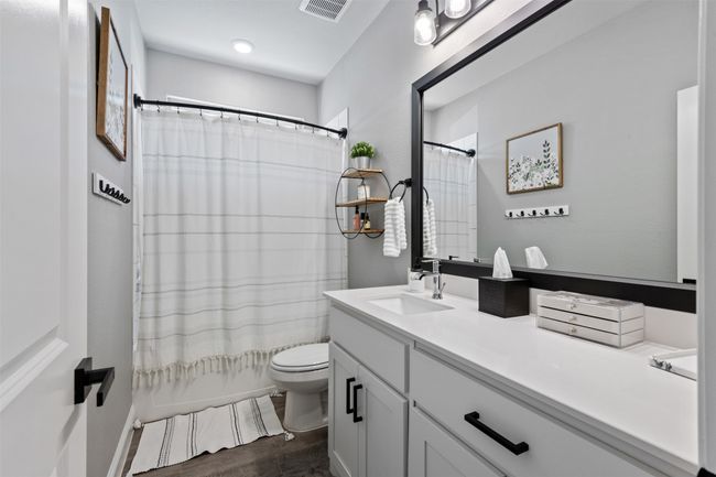 Full bathroom with visible vents, shower / bathtub combination with curtain, toilet, vanity, and wood finished floors | Image 5