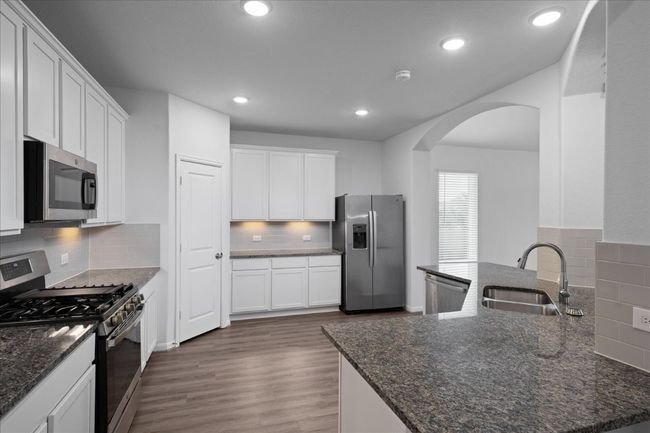 Kitchen with stainless steel appliances, a sink, arched walkways, tasteful backsplash, and recessed lighting | Image 10