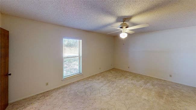 Empty room with ceiling fan, carpet, and a textured ceiling | Image 17
