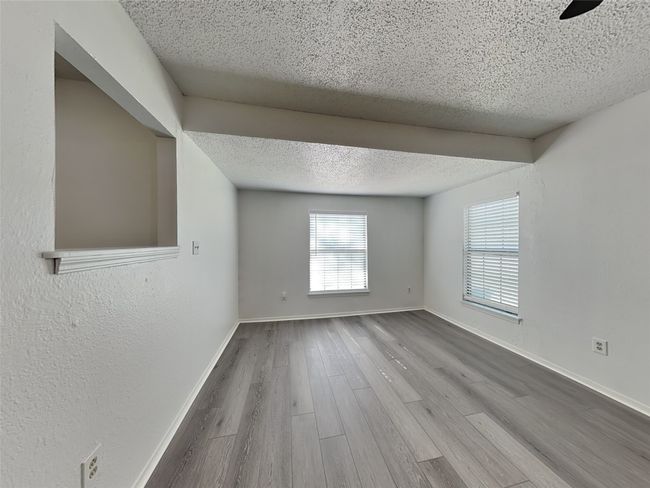 Unfurnished room with a textured ceiling, wood finished floors, baseboards, and a textured wall | Image 11