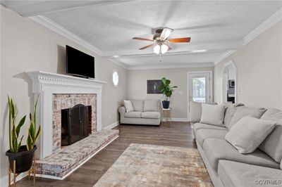 Living room with ornamental molding, a brick fireplace, ceiling fan, and LVP | Image 3