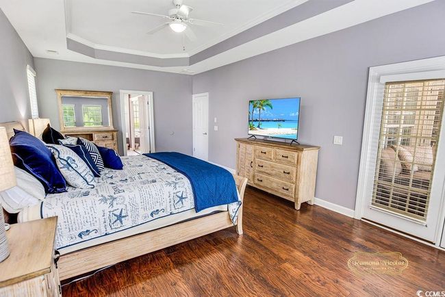 Bedroom featuring wood finished floors, a raised ceiling, ensuite bath, and ornamental molding | Image 20