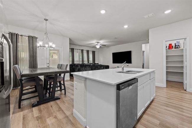 Kitchen with dishwashing machine, a sink, a chandelier, white cabinetry, and light wood-style floors | Image 15