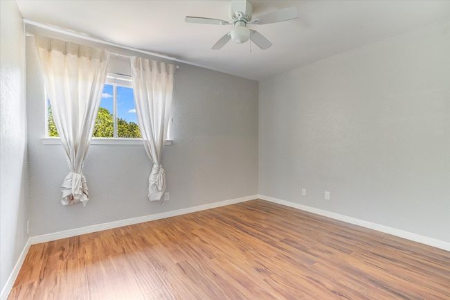 Empty room featuring wood finished floors, baseboards, and a ceiling fan | Image 12