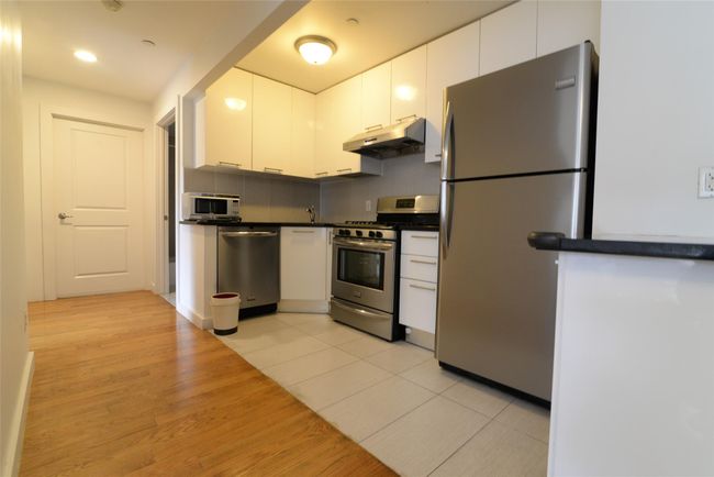 Kitchen with stainless steel appliances, under cabinet range hood, dark countertops, white cabinetry, and recessed lighting | Image 6