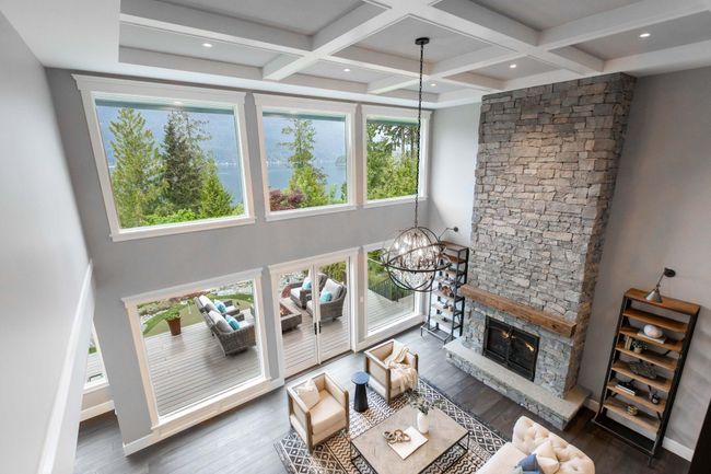 Living room with a chandelier, wood finished floors, beamed ceiling, a fireplace, and coffered ceiling | Image 5