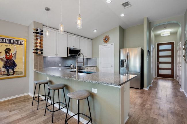 Kitchen with light wood-type flooring, a peninsula, visible vents, lofted ceiling, and appliances with stainless steel finishes | Image 5