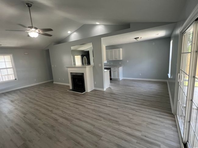 Unfurnished living room with vaulted ceiling, wood finished floors, a ceiling fan, a fireplace, and recessed lighting | Image 4