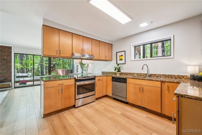Kitchen featuring a peninsula, a sink, a healthy amount of sunlight, under cabinet range hood, and appliances with stainless steel finishes | Image 29