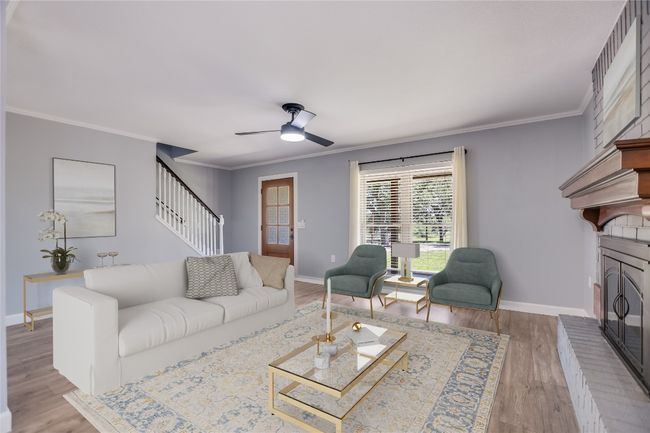 Living room with stairway, ceiling fan, a fireplace, ornamental molding, and wood finished floors | Image 8