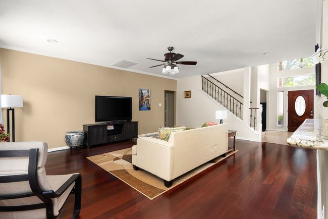 Living area with visible vents, baseboards, ceiling fan, stairs, and wood-type flooring | Image 16