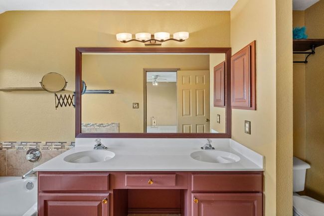 Full bath with double vanity, ceiling fan, and a bath | Image 28