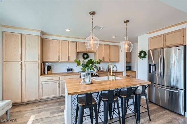 Kitchen with appliances with stainless steel finishes, butcher block countertops, light brown cabinetry, a sink, and recessed lighting | Image 13