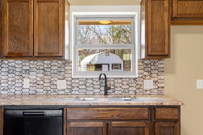 Kitchen featuring black dishwasher, light countertops, a sink, and decorative backsplash | Image 15