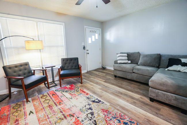 Living room featuring light wood-type flooring, ceiling fan, a textured ceiling, and baseboards | Image 4