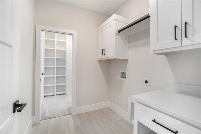 Clothes washing area with hookup for an electric dryer, cabinet space, washer hookup, and baseboards | Image 22