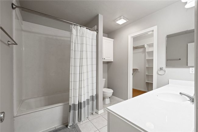 Bathroom with vanity, toilet, shower / tub combo, tile patterned flooring, and baseboards | Image 13