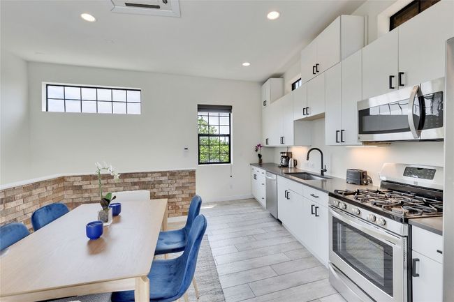Kitchen featuring appliances with stainless steel finishes, white cabinetry, recessed lighting, light wood-type flooring, and dark countertops | Image 24