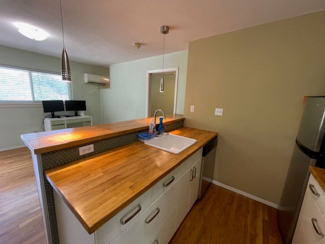 Kitchen featuring wood counters, an AC wall unit, a peninsula, and dishwasher | Image 5