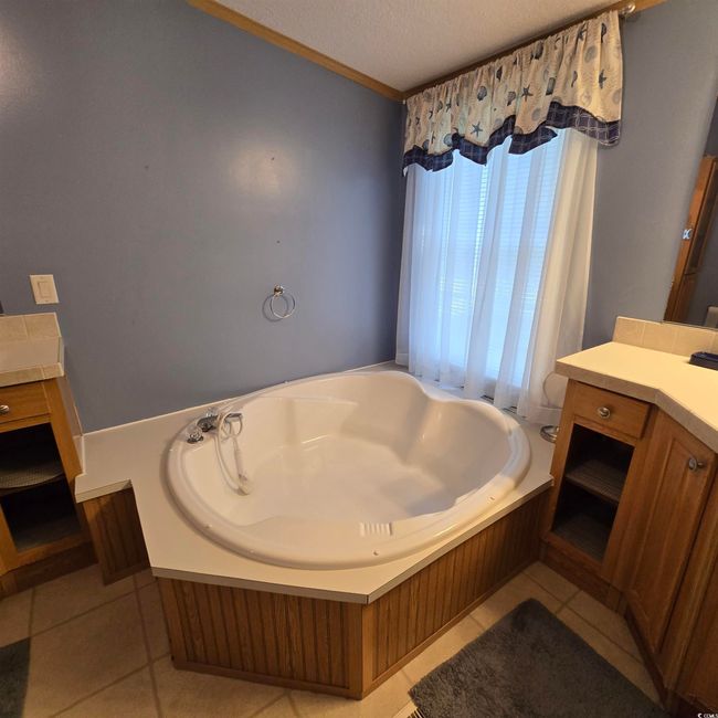 Full bathroom with a garden tub, a textured ceiling, vanity, tile patterned flooring, and crown molding | Image 24