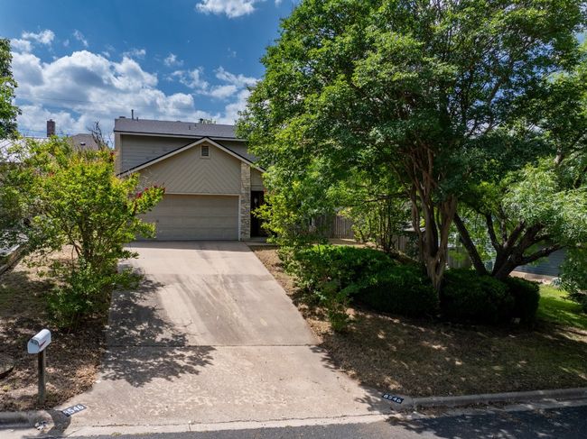 View of property hidden behind natural elements with driveway, an attached garage, and stone siding | Image 21