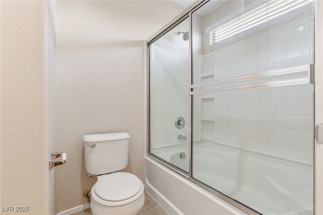 Bathroom featuring bath / shower combo with glass door and tile patterned floors | Image 13