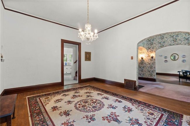 Dining Room featuring arched walkways, baseboards, a chandelier, crown molding, and hardwood floors. | Image 9