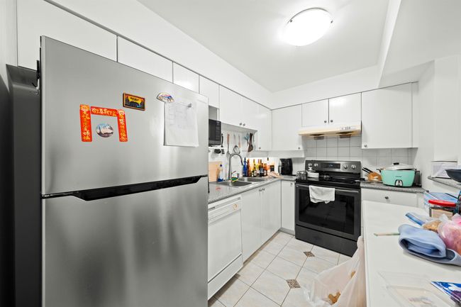 Kitchen with stainless steel appliances, a sink, light tile patterned flooring, white cabinetry, and under cabinet range hood | Image 5