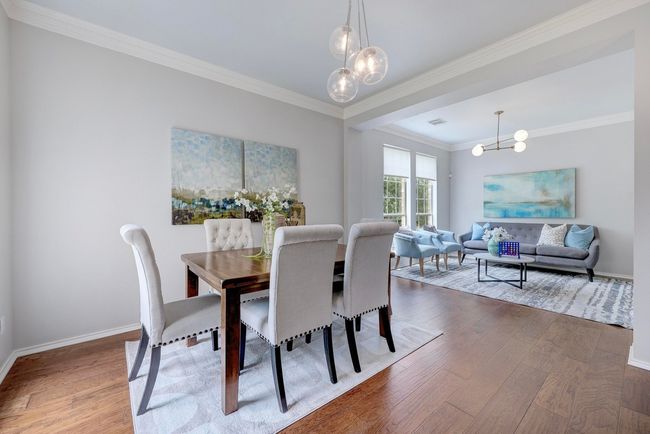 Dining space with a chandelier, wood finished floors, ornamental molding, and baseboards | Image 5