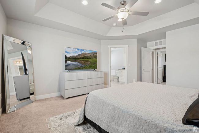 Bedroom with light colored carpet, a raised ceiling, ensuite bathroom, recessed lighting, and a ceiling fan | Image 19