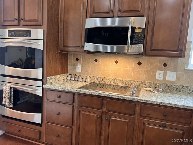 Kitchen with light stone counters, stainless steel appliances, dark hardwood / wood-style flooring, and tasteful backsplash | Image 20