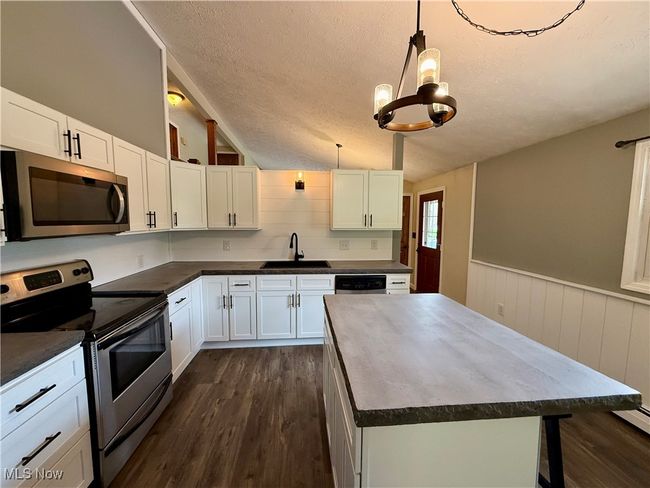 Kitchen featuring dark wood-style floors, a sink, appliances with stainless steel finishes, and dark countertops | Image 17