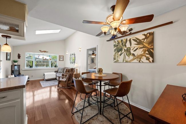 Dining space featuring ceiling fan, baseboards, dark wood finished floors, and lofted ceiling with skylight | Image 10