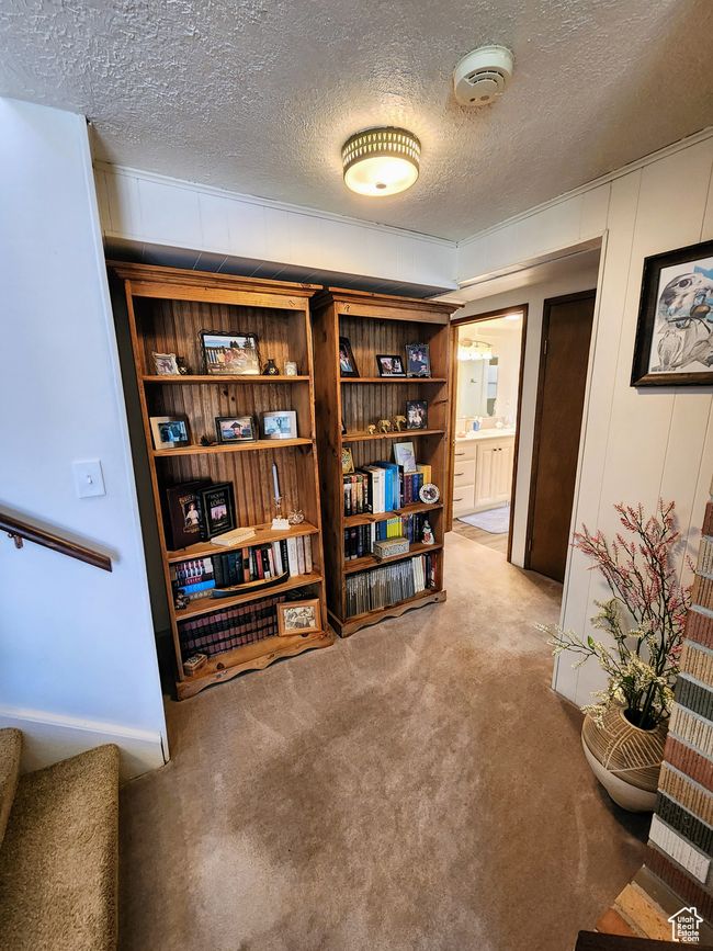 Interior space featuring a textured ceiling, light carpet, and stairway | Image 33