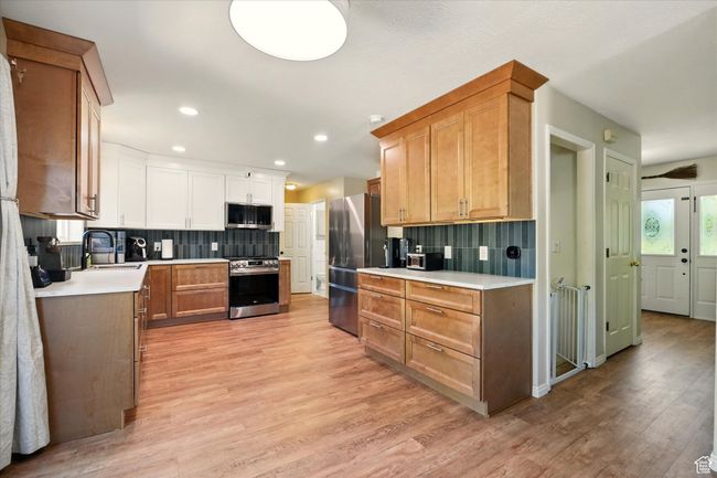 Kitchen featuring stainless steel appliances, light countertops, a sink, light wood-style flooring, and recessed lighting | Image 8
