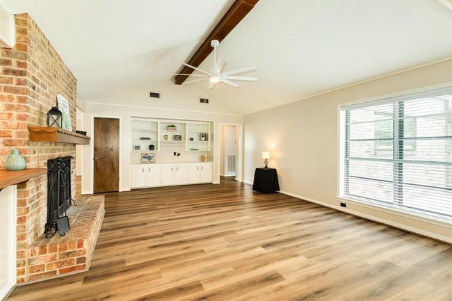 Vaulted ceiling with a large ceiling fan keep this space cool in the summer. Sit and relax in front of the cozy fire in the raised hearth brick fireplace in the winter. Expansive built in shelving unit just waiting to display all your treasures. LVP flooring throughout the living areas. | Image 13