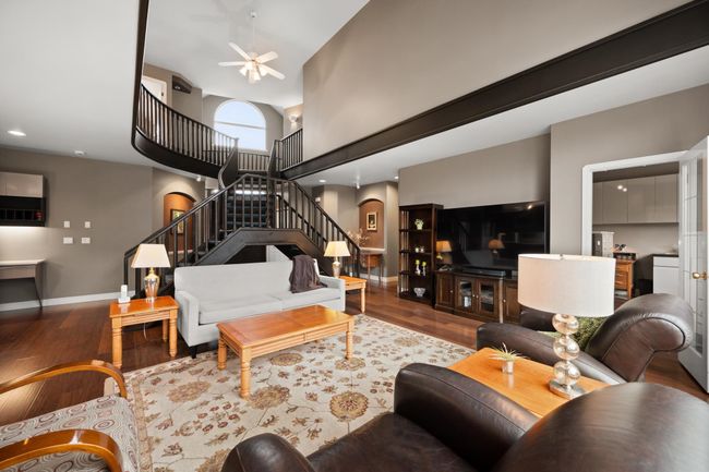 Living area featuring stairway, wood finished floors, baseboards, a high ceiling, and arched walkways | Image 8