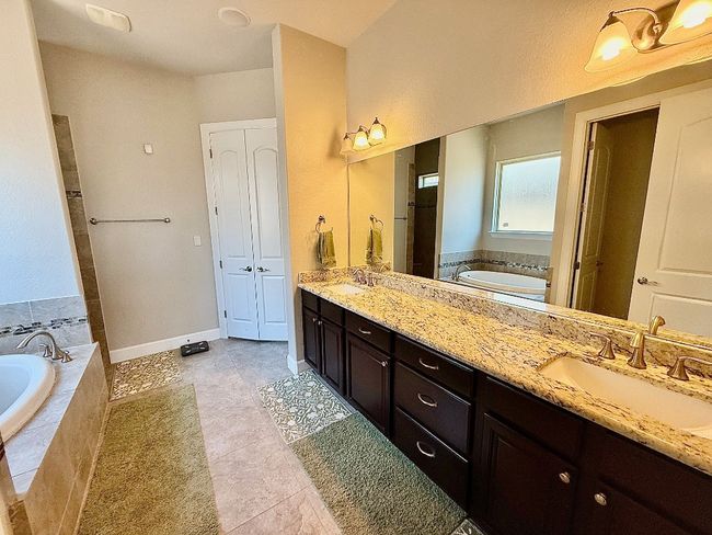 Bathroom featuring double vanity, a bath, tile patterned flooring, and tiled shower | Image 10