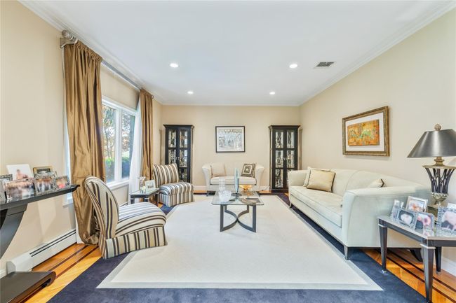 Living area featuring a baseboard radiator, wood finished floors, recessed lighting, and crown molding | Image 6