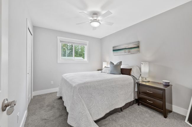 Bedroom with a closet, light colored carpet, baseboards, and a ceiling fan | Image 26