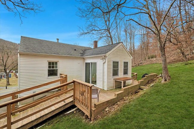 Back of house with a lawn, a chimney, a deck, and roof with shingles | Image 19