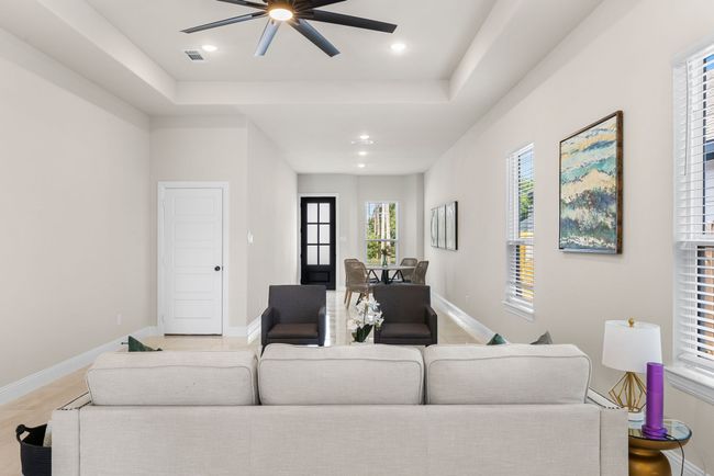 Living room with a raised ceiling, a ceiling fan, visible vents, and baseboards | Image 12