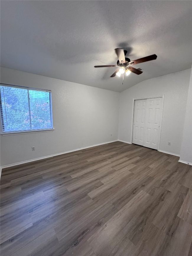 Unfurnished bedroom featuring dark wood finished floors, a ceiling fan, a closet, and lofted ceiling | Image 31