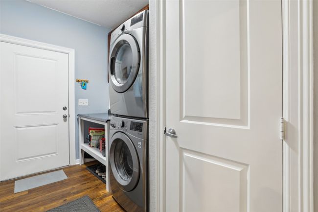 Laundry room featuring stacked washer / drying machine, wood plank laminate flooring, and laundry area | Image 16